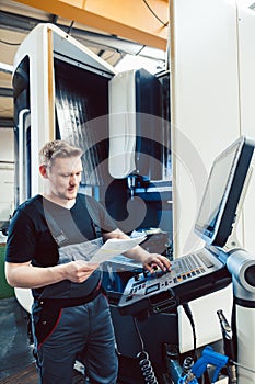 Worker in industrial workshop programming a cnc machine