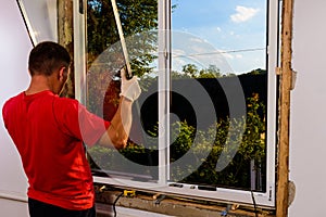 The worker inserts glass into the window frame, triple glazing of the plastic window, insulation and insulation