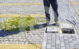 Worker inserts a yellow and green electric cable on the ground in an inspection line of the power line