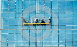 Worker inspecting glass window installation of tall glass exterior office building. Tall glass building cleaning. Working at high