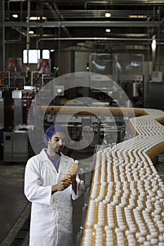 Worker inspecting orange juice bottle at bottling plant