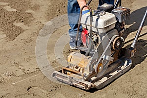 A worker inspects an old gas compactor to compact sandy soil