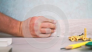 Worker instal plastic skirting board on laminate flooring. Renovation of baseboard at home.