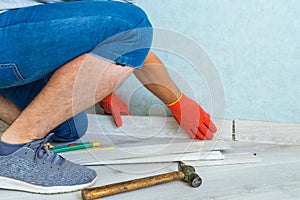 Worker instal plastic skirting board on laminate flooring. Renovation of baseboard at home.