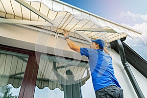 Worker install an awning on the house wall over the terrace