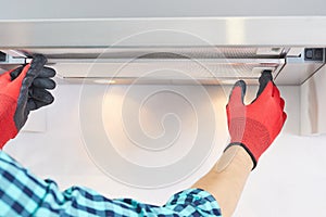 Worker install filter in home range hood at kitchen. Handyman removing filter from a exhaust hood. Cooker hood repair