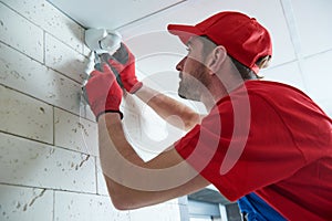 Worker installing or adjusting motion sensor detector on the ceiling photo