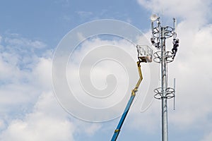 Worker installing antenna on tall telecommunication tower