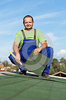 Worker installing bitumen roof shingles