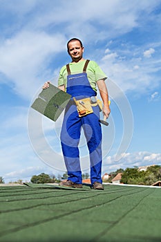 Worker installing bitumen roof shingles