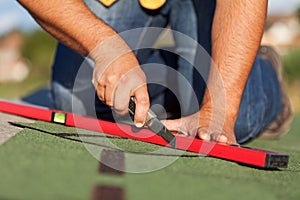 Worker installing bitumen roof shingles