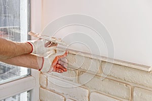 A worker is installing brick tiles on the wall