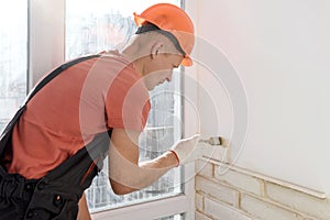 The worker is installing brick tiles on the wall