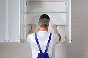 Worker installing cabinet with shelves