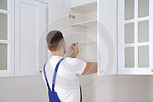 Worker installing cabinet with shelves in kitchen