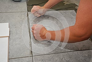 Worker installing ceramic tile on the floor, bathroom flooring
