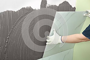 Worker installing ceramic tile on wall, closeup