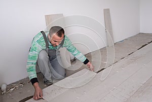 Worker installing the ceramic wood effect tiles on the floor