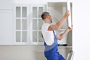 Worker installing door of cabinet