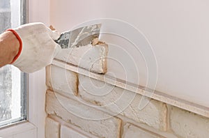 A worker is installing  brick tiles on the wall