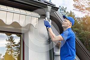 Worker installing house roof gutter system