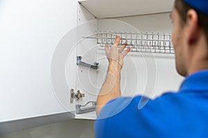 Worker installing kitchen cabinet dish rack