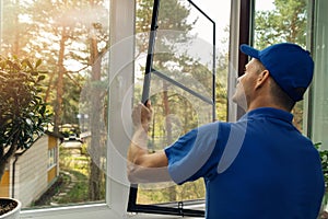 Worker installing mosquito net wire screen on house window