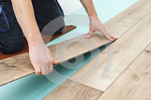 Worker installing new laminated wooden floor. Easy and quick installation of the flooring. Connecting laminate locks. DIY floating