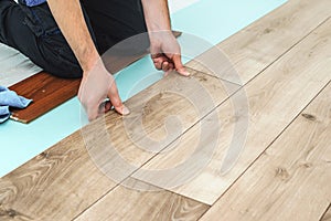 Worker installing new laminated wooden floor. Easy and quick installation of the flooring. Connecting laminate locks