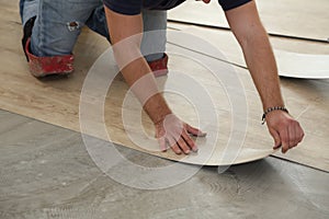 Work on laying flooring. Worker installing new vinyl tile floor. photo