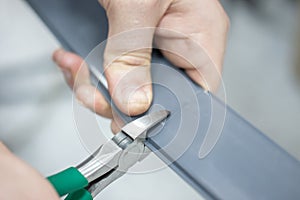 Worker installing plastic wires organisation at floor. uses screwdriver, drill, nippers, dowel and screws to montage.