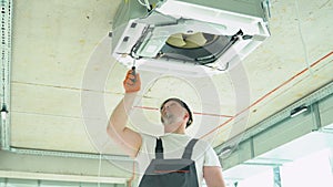 Worker installing or repairing ceiling air conditioning unit