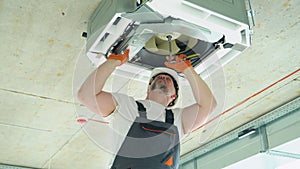 Worker installing or repairing ceiling air conditioning unit