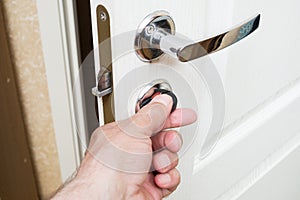 Worker installing or repairing new lock and door knob with screwdriver.