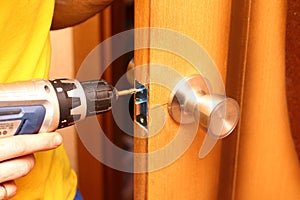 Worker installing or repairing new lock and door knob with screwdriver