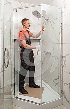 The worker is installing a shower in the shower enclosure