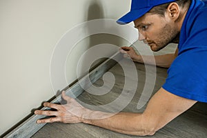 Worker installing skirting board, baseboard