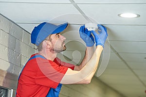 Worker installing smoke detector on the ceiling