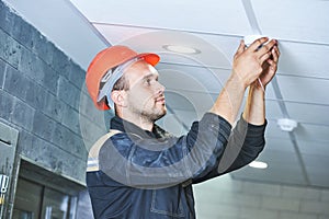 Worker installing smoke detector on the ceiling