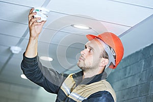 Worker installing smoke detector on the ceiling