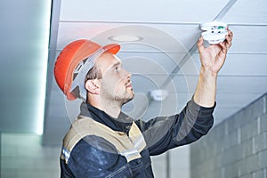 Worker installing smoke detector on the ceiling