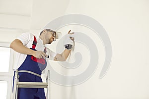 Worker installing a surveillance CCTV dome camera on the wall inside the building