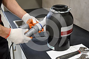 A worker is installing a waste shredder for the kitchen sink photo