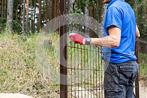 Worker installing welded metal mesh fence