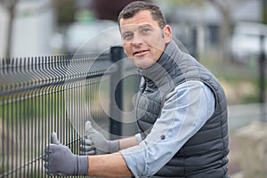 worker installing welded metal mesh fence