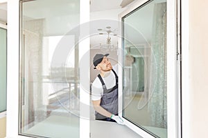 Worker in installing white plastic upvc window on house photo