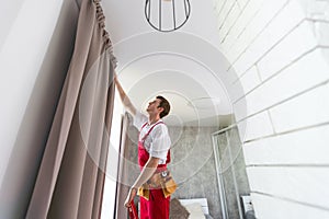 worker installing window curtain rod on the wall