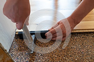 Worker installing wood parquet board during flooring work with hammer