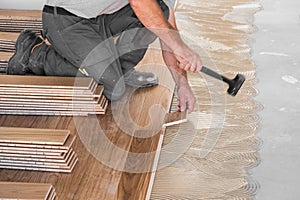 Worker installing wooden flooring boards
