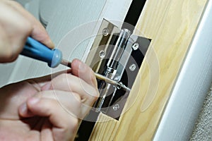 Worker installs door hinges with a screwdriver